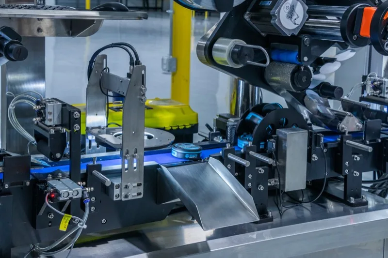 Close-up of a can with a blue lid riding the conveyor of a labeling machine